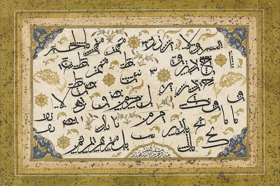 Feuille de calligraphie arabe à l'encre noire sur papier crème, encadrée de décors floraux dorés