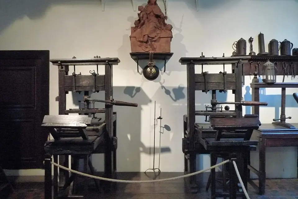 Deux presses à imprimer anciennes en bois, avec leurs leviers et leurs plateaux, dans une salle de musée