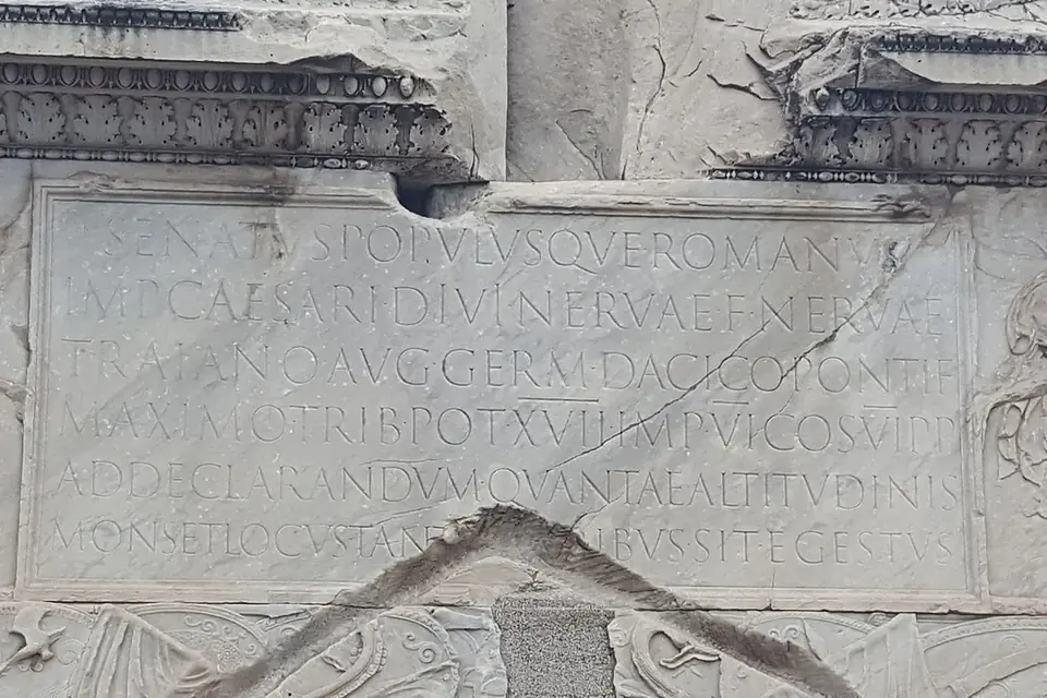 Inscription latine en capitales gravées dans le marbre au-dessus d'une porte, à la base de la colonne Trajane à Rome